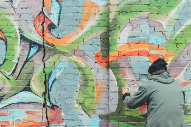 istock back view of man painting colorful graffiti on wall 966243878