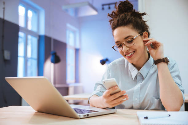 istock Girl wearing glasses smiling while looking at her phone 966247422