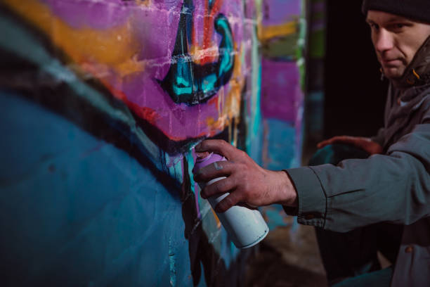 istock man painting graffiti with aerosol paint on wall at night 966252254