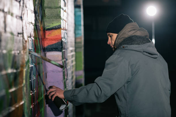 graffiti de pintura do artista de rua com tinta aerossol na parede à noite - graffiti men wall street art - fotografias e filmes do acervo