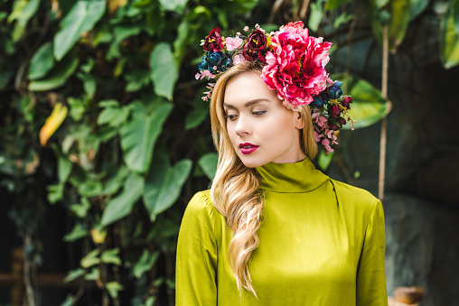 attractive young woman with floral wreath with green rainforest on background