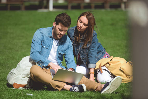 istock young tourists with backpacks and laptop sitting on grass 966261442