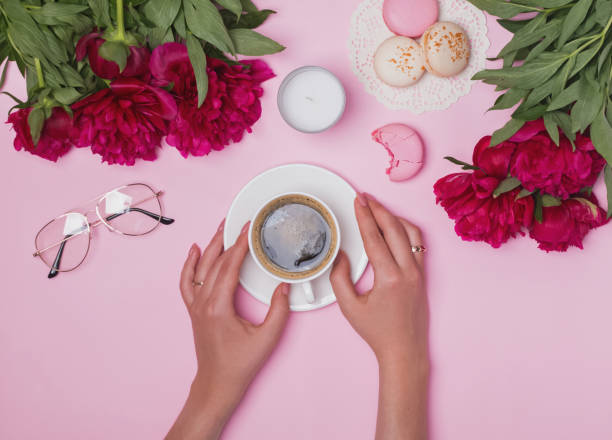 istock Woman's hands holding coffee on the table with peonies and macarons 966262078