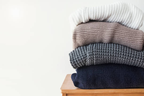 istock Stack of cozy winter sweaters on the white wall background. 966262624