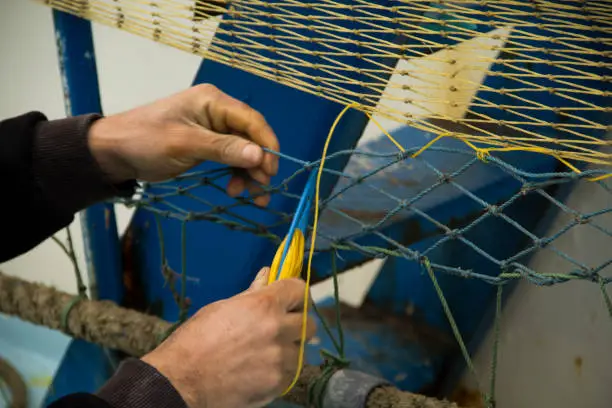 a fisherman knitting fishing-net