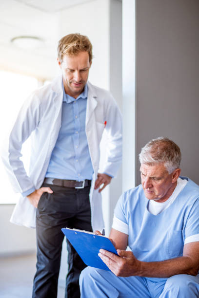 istock Doctor looking at colleague writing on clipboard 966267800