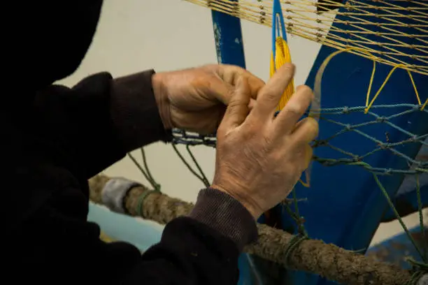 a fisherman knitting a fishing-net