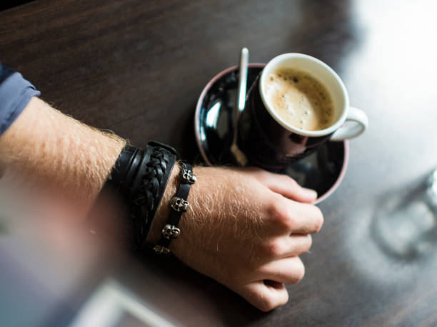Businessman taking a break at the office as he enjoys a cup of hot aromatic coffee, close up view of his hands