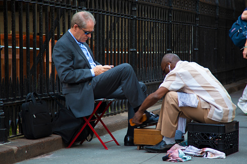 Shoeshine in the city. A black man polishes the shoes of a businessman