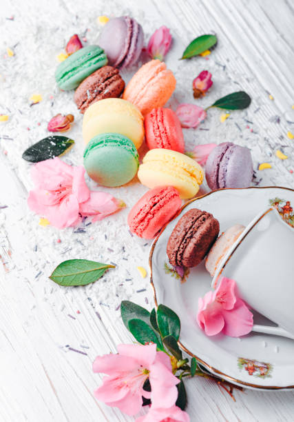 Tea cup, macaroons, flowers and leaves on a white background.