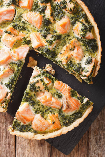 istock Sliced Quiche with salmon, spinach and cream close-up. vertical top view 966281456