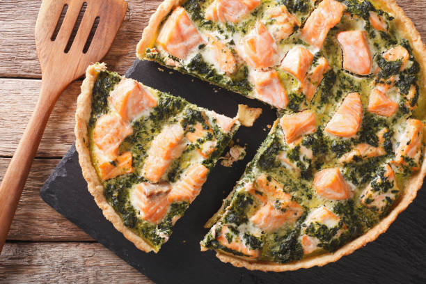 istock Savory food: sliced tart with salmon, spinach and cream close-up. Horizontal top view 966284188