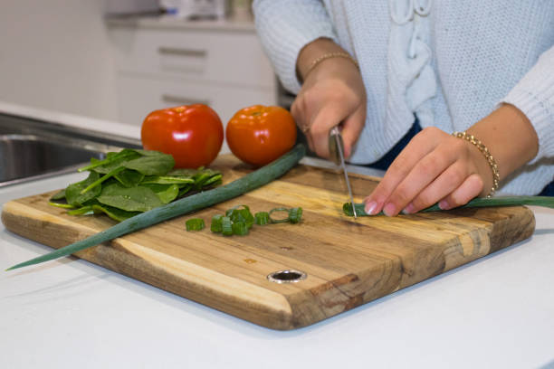 istock Womans hands chopping vegetables on wooden chopping board 966285300