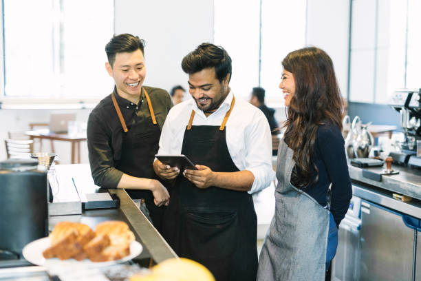 Quick Staff Meeting Cafe owner explaining menu to workers using a digital tablet. small business malaysia stock pictures, royalty-free photos & images