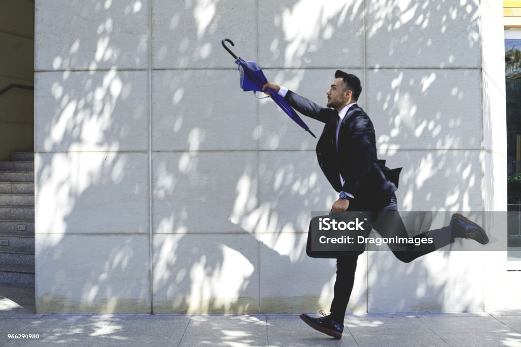 Chasing taxi Businessman with umbrella running to catch taxi or bus Chasing Stock Photo