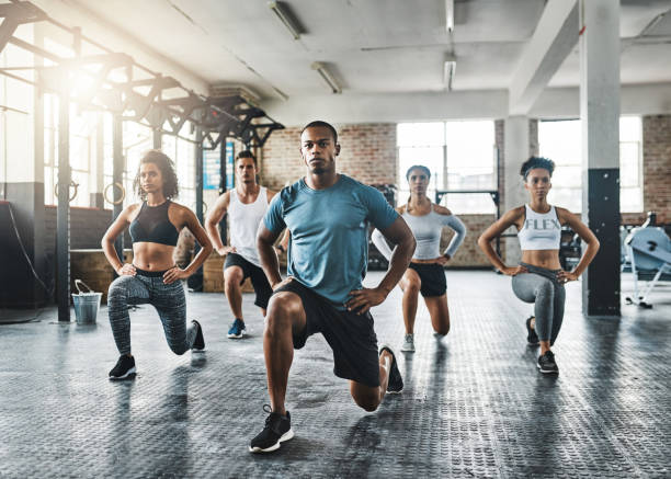 Every step taken towards fitness pays off Shot of a group of young people doing lunges together during their workout in a gym exercise class photos stock pictures, royalty-free photos & images