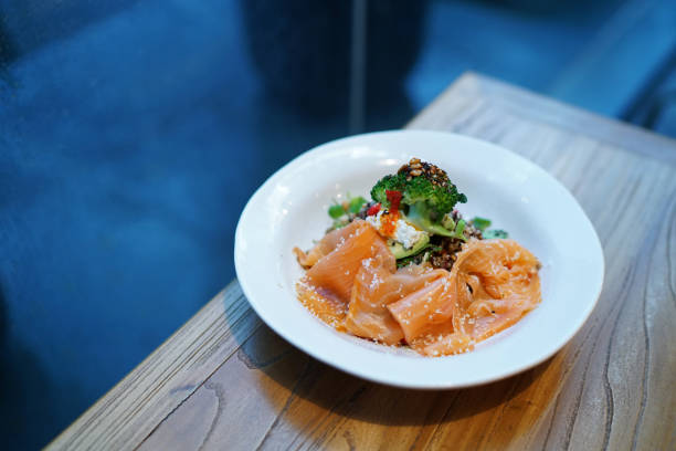 Smoked salmon salad, combination of avocado roasted beets, mixed pulses and grains, sprouting broccoli and chili dressing on wooden table and copy space.