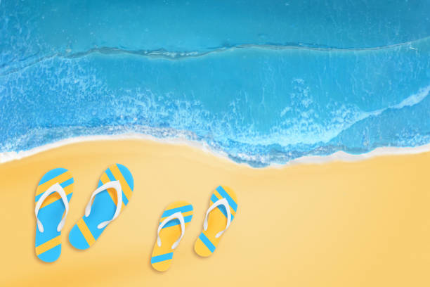 istock Slippers from a couple on the beach. Top view. 966306536