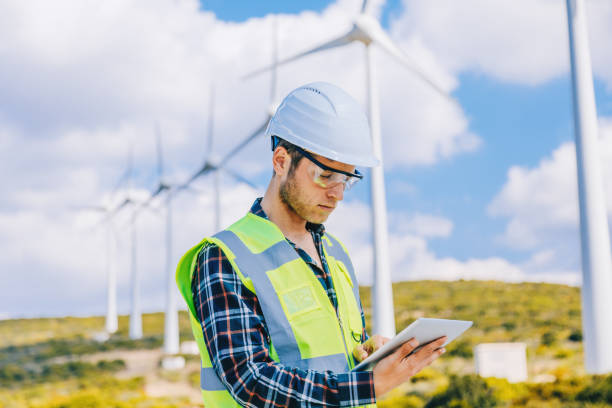 istock Young engineer man looking and checking wind turbines at field 966313200