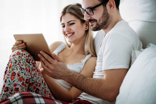 istock Young happy couple using tablet in bedroom 966313220
