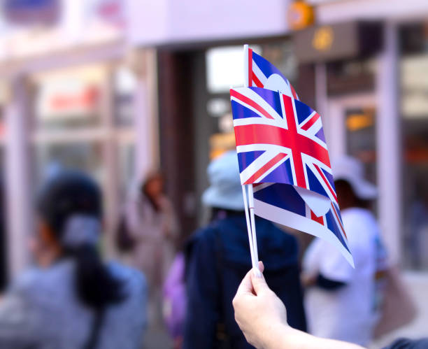 istock Hand proudly holding up 2 union Jack flags 966318392