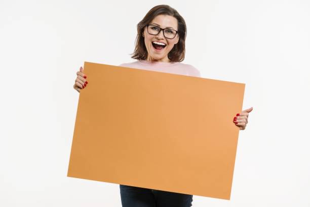 sonriente mujer envejecida media con cartelera hoja naranja, cartel en fondo blanco - businesswoman advertise placard advertisement fotografías e imágenes de stock