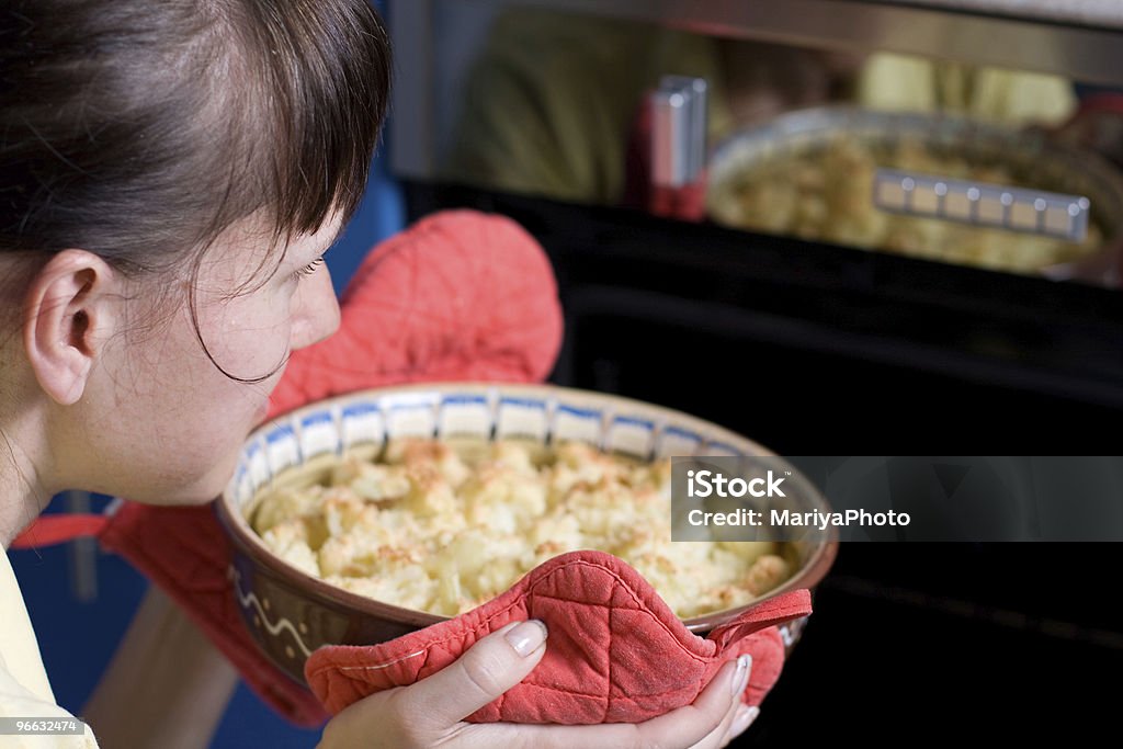 Young woman putting cauliflower into the stove  Adult Stock Photo