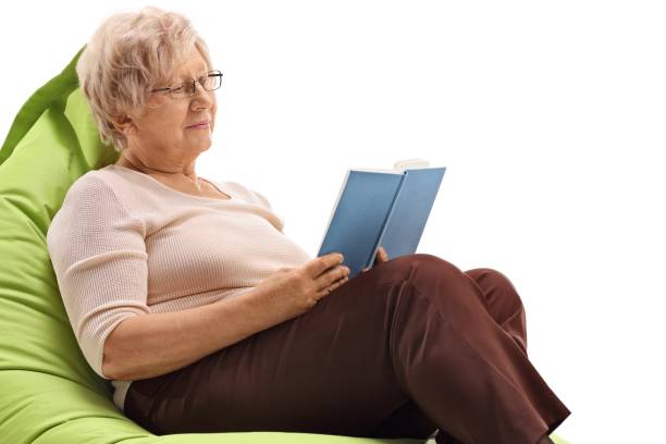 istock Mature woman sitting on a beanbag and reading a book 966332080