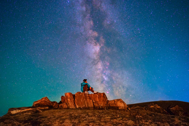 istock Blue stars, the Milky Way, A man sitting alone on a hill 966345600