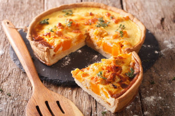 Sliced Savory pie with pumpkin, cheese, chicken and herbs closeup. Horizontal Sliced Savory pie with pumpkin, cheese, chicken and herbs closeup on the table. Horizontal quiche stock pictures, royalty-free photos & images