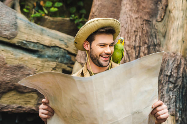 istock happy young man with parrot on shoulder and map in jungle 966346240