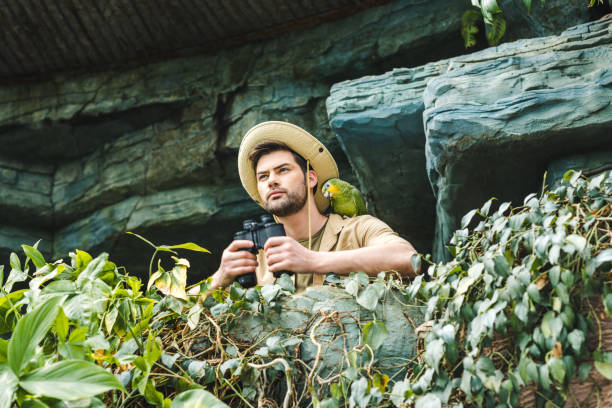 istock bottom view of young man with parrot on shoulder and binoculars looking at camera 966347178
