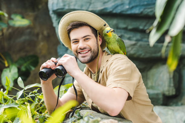 istock handsome young man with parrot on shoulder and binoculars looking at camera 966347308