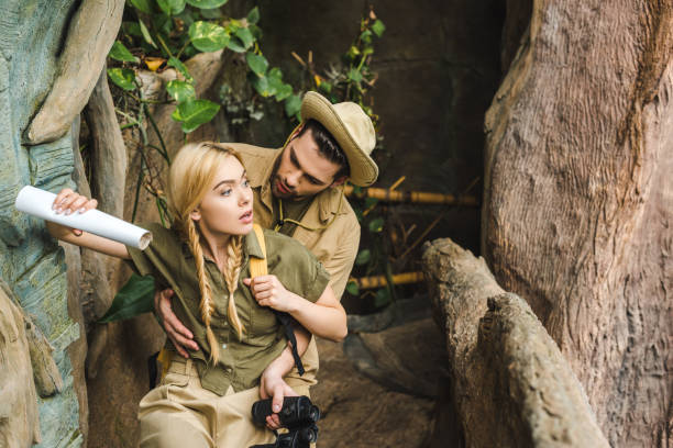 istock young man supporting his girlfriend while they hiking in jungle in jungle 966350394