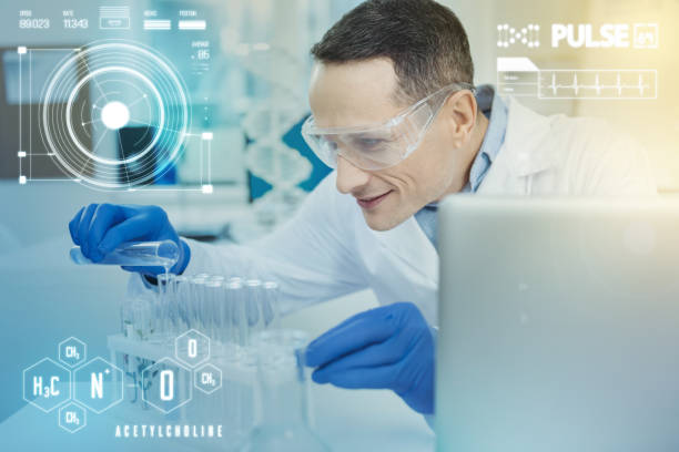 istock Careful scientist smiling while pouring liquids into his test tubes 966356196