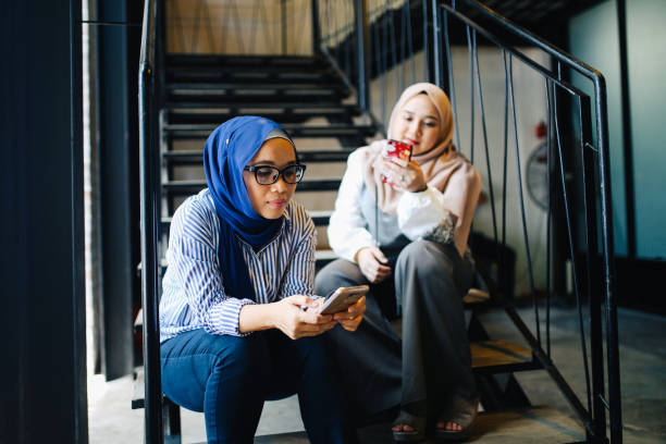 istock Two Malaysian women having a break from work, texting on the phones 966358672