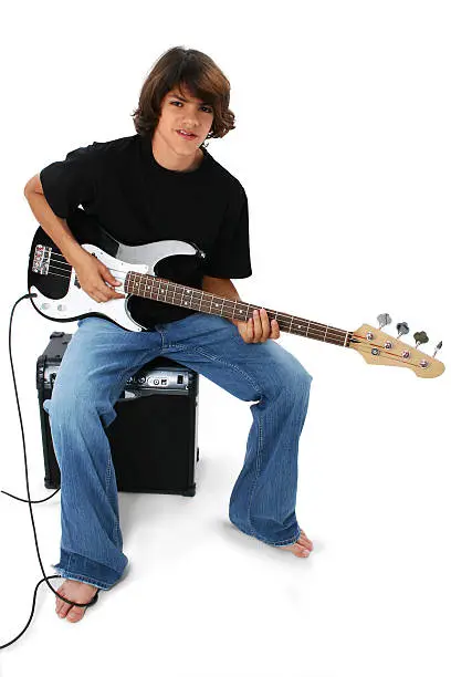 Photo of Boy With Black And White Bass Guitar Sitting On Amp