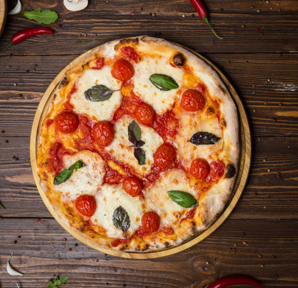 rustic italian pizza Margarita with mozzarella, cherry tomatoes and basil leaves on wooden background