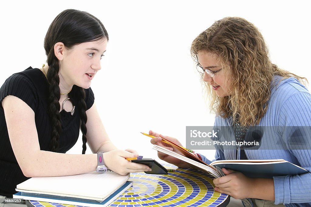 Tween Girls in Study Session Two 12 year old girls doing homework together. Shot in studio over white. Blond Hair Stock Photo