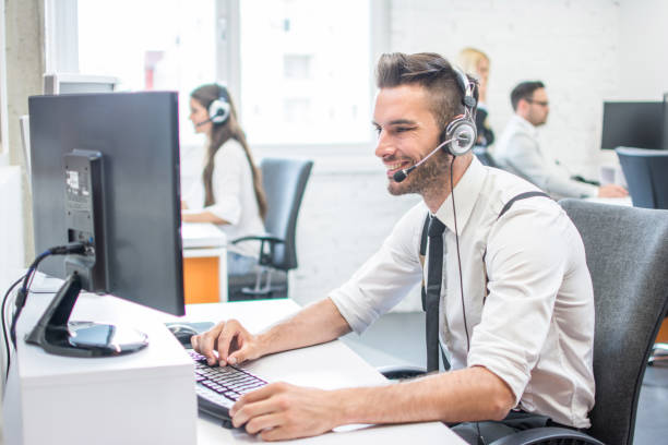 istock Handsome man in business wear with headset using computer in call center 966374128