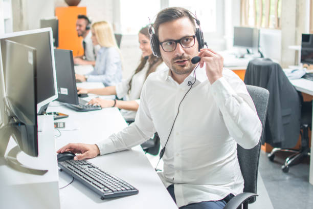 istock Call center operator with headset working in row with colleagues 966374278
