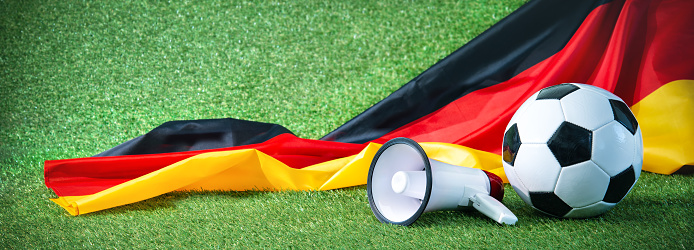 Soccer ball with german flag and megaphone on playing ground