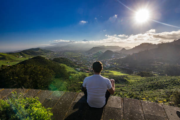 istock man sitting with view on villages and teide volcano at sunset 966390696