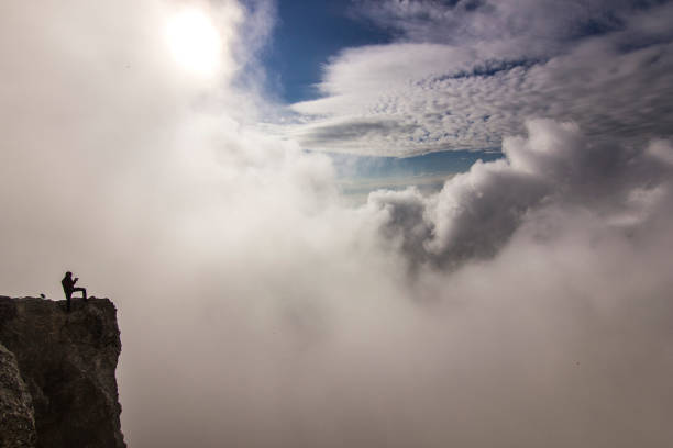 istock girl with hands up standing on a cliff in clouds 966399648
