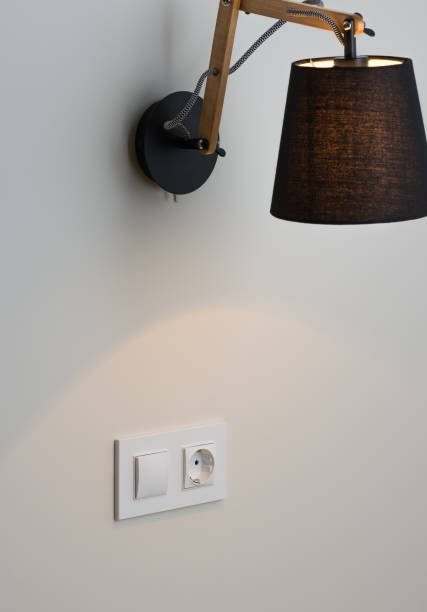istock White European electrical socket and switch on the gray wall. Stylish modern black lamp 966400108