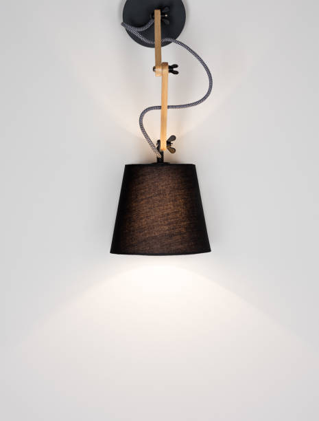 istock A glowing modern lamp on a light wall with free space. Black lamp and wooden design 966400270