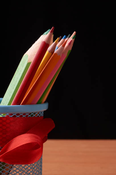 istock color pencils in tin can on wood table on black background 966404980