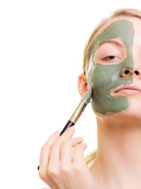 istock Woman applying with brush clay mud mask her face 966405306