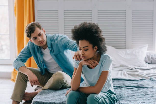 istock Man talking to his african american girlfriend sitting on bed 966411160