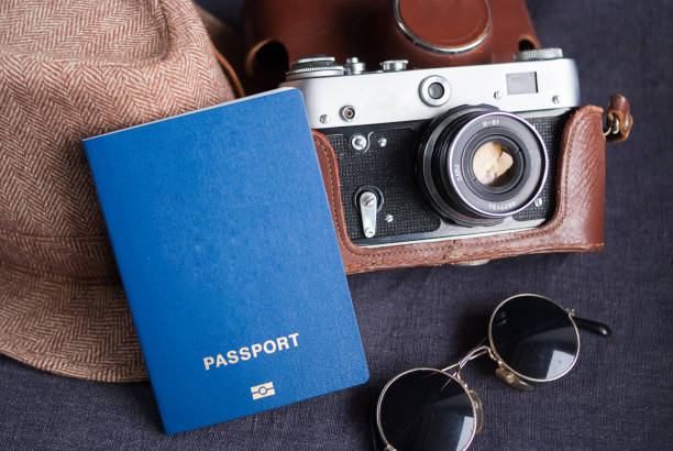 Blue blank of passport with beach hat, camera on dark background Blue blank of passport with beach hat, camera on gray background blue us passport cover stock pictures, royalty-free photos & images